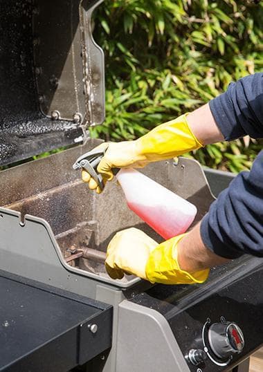 cleaner spraying a barbecue with detergent